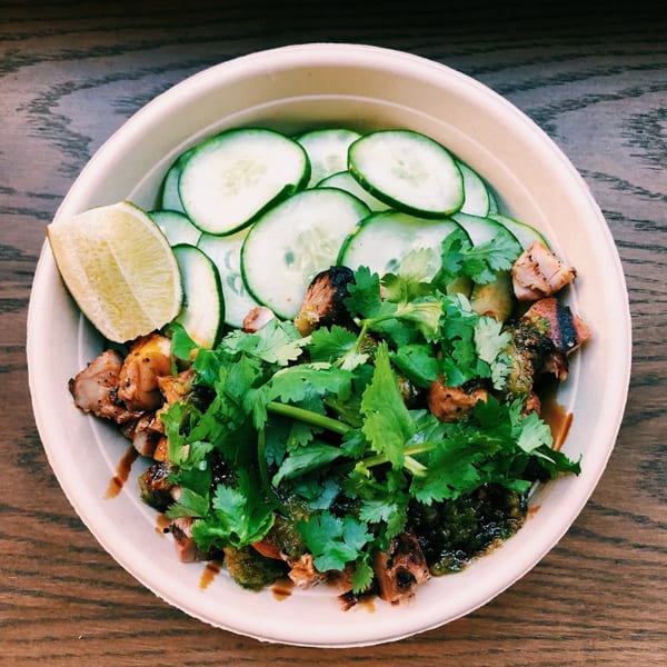 Mighty Bowl's Asian-fusion dish with chicken, cilantro, sliced cucumbers, and a lime wedge.