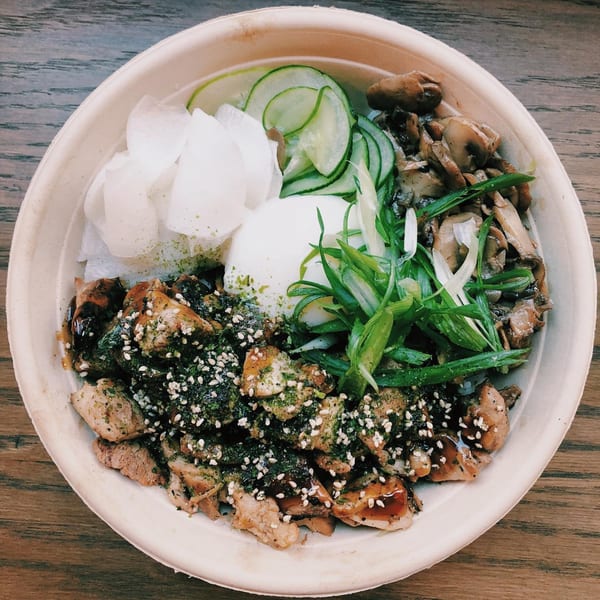 A colorful poke bowl with chicken, mushrooms, cucumbers, daikon, and a poached egg.
