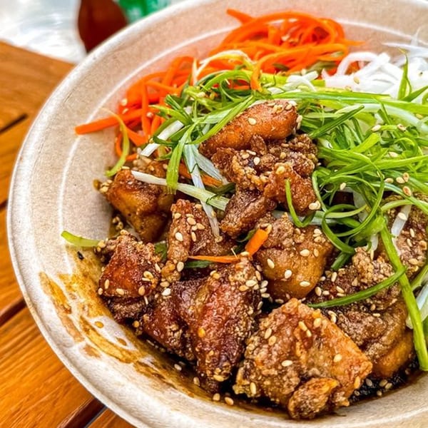 Mighty Bowl's Asian-fusion dish with crispy chicken, sesame seeds, shredded carrots, and green onions.