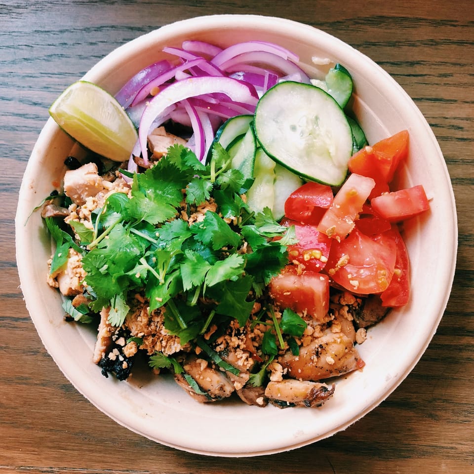 Mighty Bowl's Asian-fusion bowl with chicken, cilantro, red onion, cucumber, tomatoes, and lime.